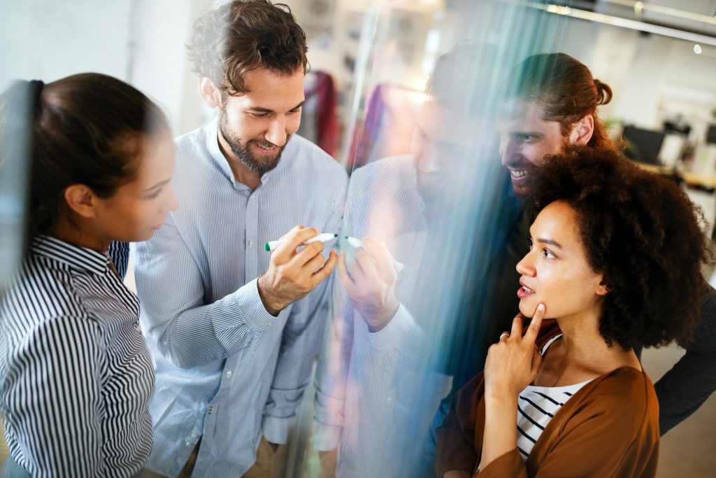 Equipo profesional debatiendo y tomando notas sobre un panel de cristal en una reunión de trabajo