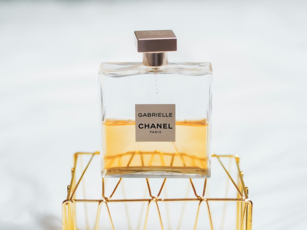 Primer plano de un frasco de perfume con etiqueta de marca sobre soporte dorado